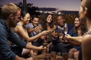 Group Of Friends Enjoying Night Out At Rooftop Bar